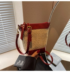 Detail of burgundy and beige straw bucket bag with adjustable leather shoulder strap
