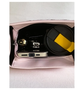 Vertikale Draufsicht zeigt den geräumigen Innenraum einer rosa Ledertasche mit Utensilien