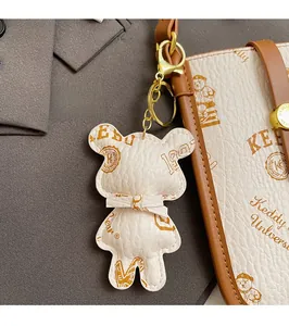 Close-up of a bear leather pendant with gold hardware on a cream crossbody bag