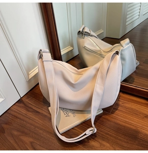 Detail view of beige lychee textured leather crescent bag with adjustable wide strap