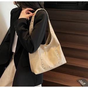 Détail d'un sac cabas en similicuir beige avec des rivets argentés et une poche frontale
