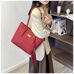 Detail of red tote bag with fishbone texture and matching pouch in a lifestyle setting