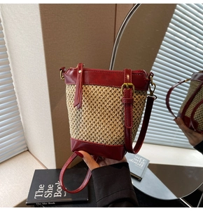 Detail of hollow straw weave bucket bag with red faux leather trim and metallic buckle