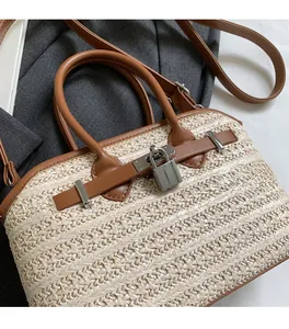 Close-up of woven straw handbag featuring brown leather trim and metallic padlock detail