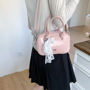 Detail der rosa Lackleder-Kissentasche mit Spitzen-Perlen-Anhänger und Knotengriffen