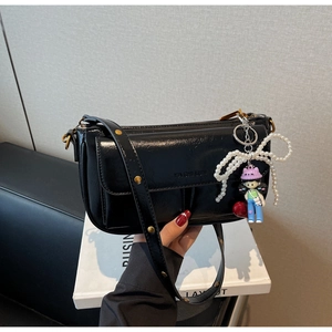 Detail of black leather pillow bag with pearl bow and cartoon doll charm accessories