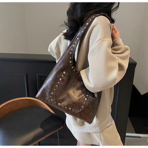 Gros plan d'un cabas en cuir marron vintage avec rivets porté sur l'épaule