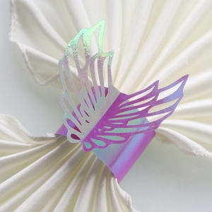 Close-up of rainbow iridescent laser-cut angel wing napkin ring on white fabric