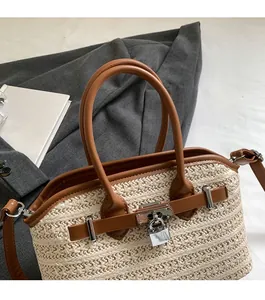 Detailed view of woven straw handbag with brown leather straps and silver padlock clasp