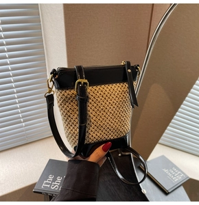 Detail of straw and black leather bucket bag with zipper and adjustable strap