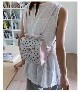 Detail eines rosa Rucksacks mit Schleifen-Print auf Holztisch mit Wohnzimmer-Dekor