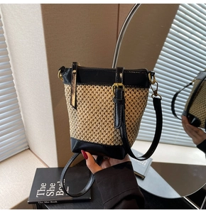 Detail of woven straw bucket bag with black leather trim and secure golden zipper closure