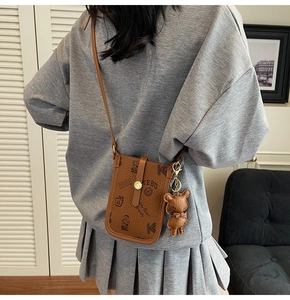 Detail view of brown faux leather crossbody phone bag with teddy bear university prints