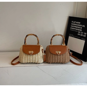 Detail view of woven straw shoulder bag with bamboo handle and gold lock closure