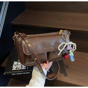 Detail of dark brown vintage crossbody bag with stylish pearl and cartoon charms