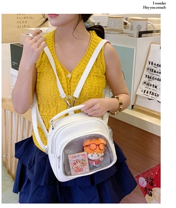 Detail of white leather ita bag with transparent window featuring a plush toy decoration