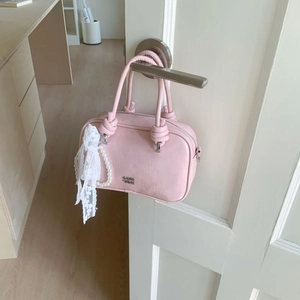Detail der rosa Boston Bag mit Knotengriffen und weißem Perlenanhänger aus Spitze