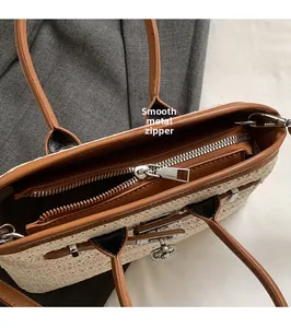 Detail of silver smooth zipper and woven straw texture with brown leather accents
