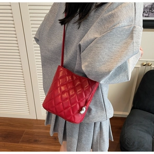 Dettaglio della mini borsa a tracolla rossa trapuntata con finitura lucida e ciondolo cuore
