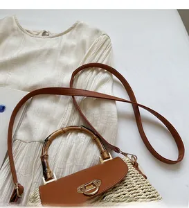 Detail of woven straw handbag featuring bamboo handle and golden horseshoe metal clasp
