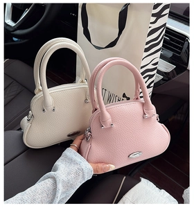 Close-up of mini lychee pattern leather handbags in cream and pink on a car seat