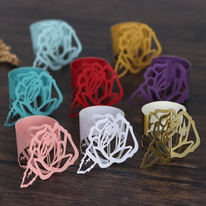 Hollow rose laser cut paper napkin rings in diverse colors on a wooden surface