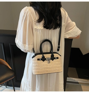 Detail of woven straw crossbody bag featuring black leather trim and metal lock closure