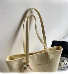 Detail of beige tote bag featuring crocodile embossed texture and adjustable gold buckle