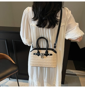 Detail of woven straw handbag featuring black leather trim and silver clasp on a model