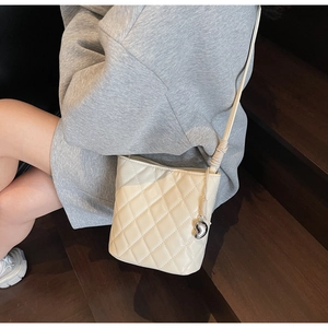 Borsa a secchiello in pelle trapuntata crema con cuore su scale di legno scuro