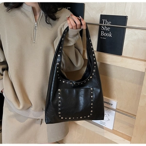 Détail des rivets argentés sur le sac cabas noir avec poche avant et poignées chic