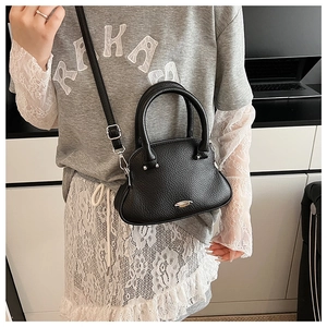 Detail of black semi-circular crossbody bag with lychee texture and silver logo
