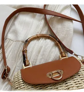 Close-up of bamboo handle and leather flap on straw woven crossbody bag for beach vacations