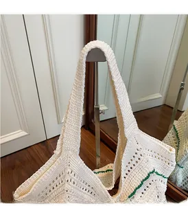 Detail of white knit tote bag with green wavy trim and hollow diamond crochet texture