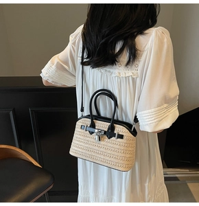 Detail of woven straw crossbody bag with black leather trim and silver metal lock closure