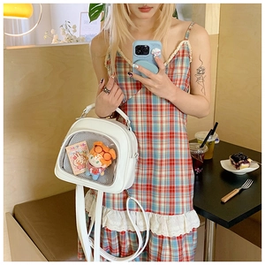 Detail of white PU leather ita-bag with transparent window and plush doll inside