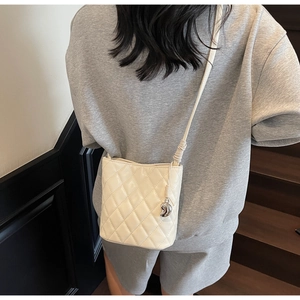 Dettaglio della borsa a spalla trapuntata beige con pendente a luna sulla spalla
