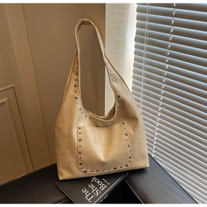 Détail du sac hobo beige avec rivets argentés et texture effet cuir sur socle