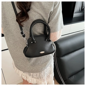 Rear view of model wearing a black pebbled leather shell bag with silver hardware detail