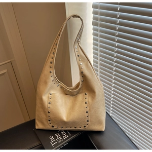 Gros plan détaillé du sac hobo en cuir beige avec clous argentés et texture grainée