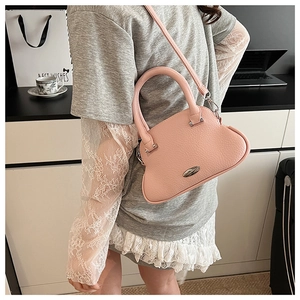 Detail of pink lychee leather handbag with unique wavy shape and olive metal accent