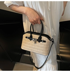 Detail of hand-woven beige crossbody bag with black leather trim and silver metal buckle