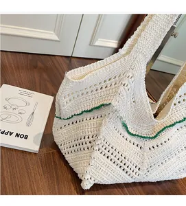 Macro detail of hand-woven hollow knit tote bag with cream texture and green wavy trim