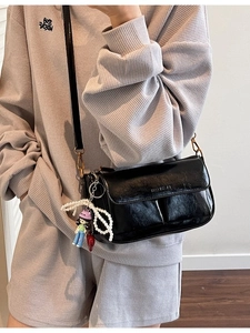 Vintage black glossy pillow bag with metal logo, pearl bow and doll charm on model