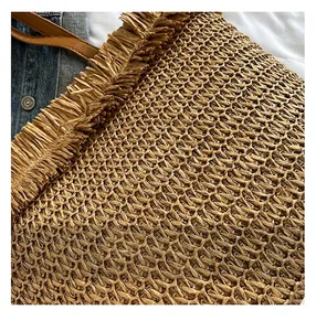 Makro-Detail der handgewebten Stroh-Tasche mit Fransenrand und Leder-Schultergurt