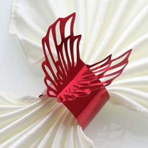 Macro shot of red butterfly napkin ring with laser-cut hollow design on white satin cloth