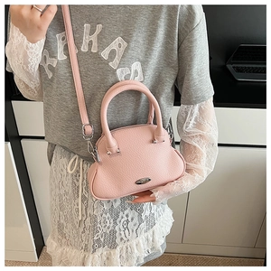 Pink lychee grain shell bag worn as a shoulder bag in a modern indoor setting