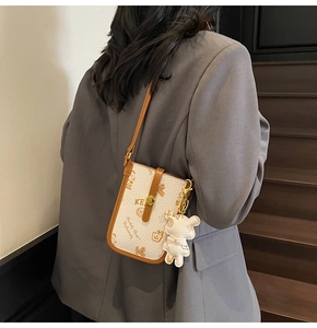 Detailed close-up of a white lychee leather mobile phone bag with brown teddy bear print