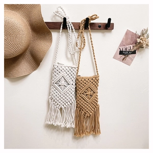 Close-up of bohemian woven straw bags with diamond patterns and long fringe tassels