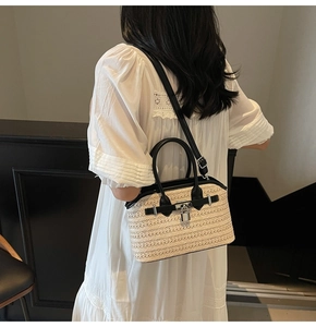 Detail of hand-woven straw bag with black leather accents and silver buckle on model